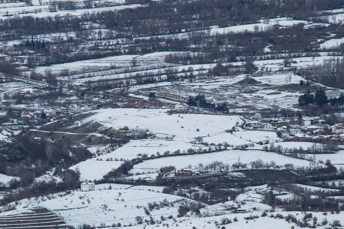 A serene winter landscape capturing snow-covered fields and a rural settlement in Sivrice, Elazığ, Turkey.