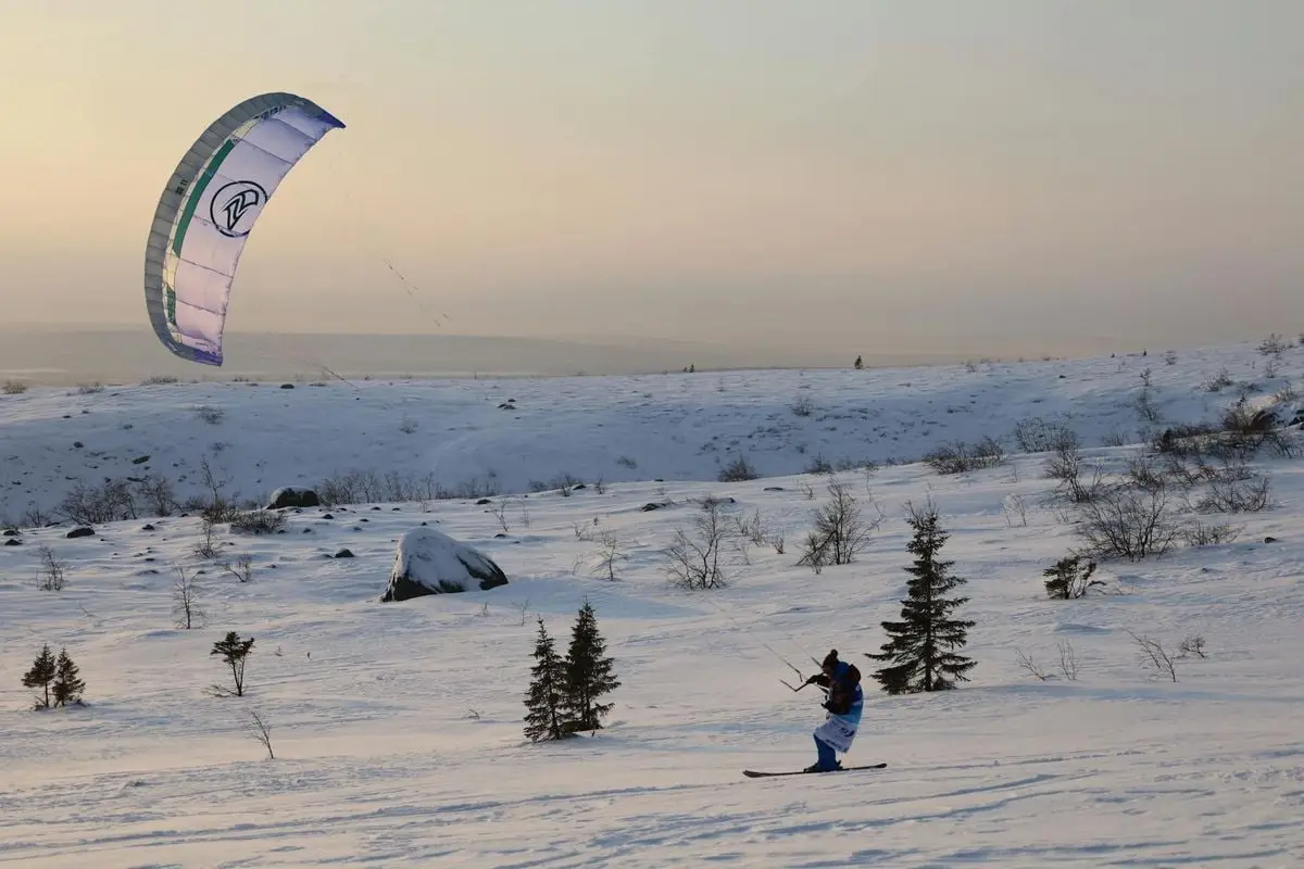 Kiteboarder enjoying a snowy winter landscape in Kirovsk, Russia.