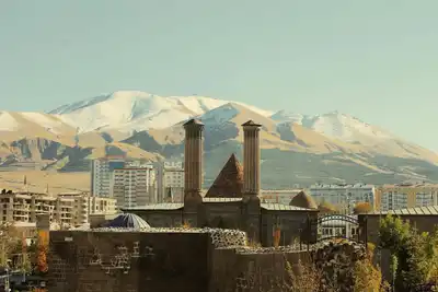 The historic Cifte Minareli Medrese with snow-covered mountains in Erzurum, Turkey.