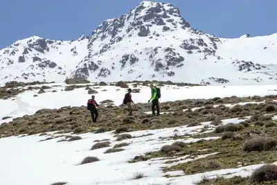 Hikers trekking through snow-covered mountains in Van, Turkey, under clear blue skies.