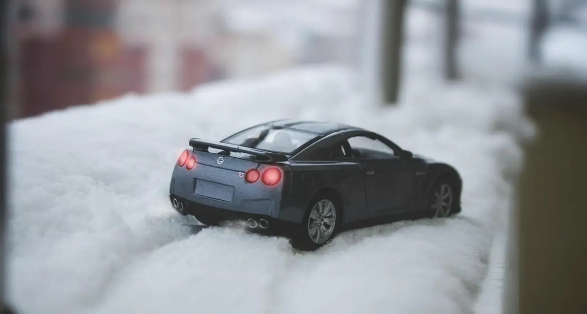 Close-up of a miniature toy car on snow, showcasing a winter scene.