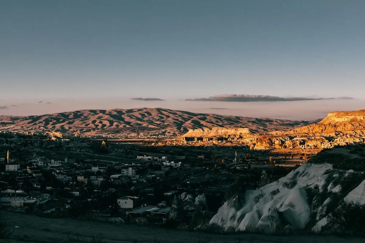 Captivating view of Goreme National Park with rocky formations and a town at sunset.