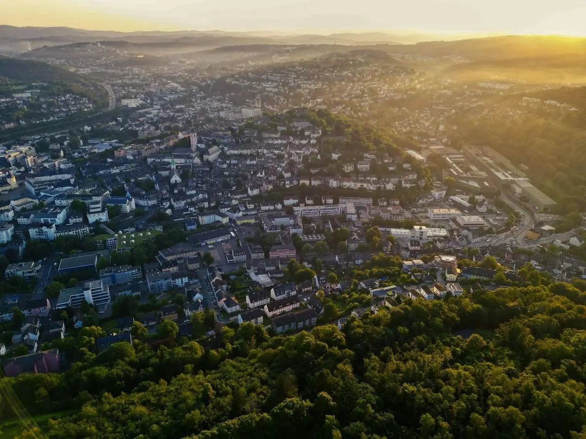 Breathtaking aerial scene of Siegen, Germany blanketed by summer twilight glow, highlighting urban and natural harmony.