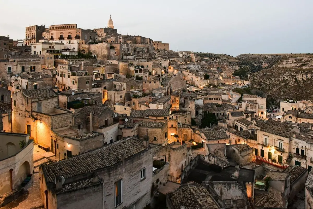 Panoramic view of Matera, Italy's ancient stone city at dusk, showcasing historic architecture.