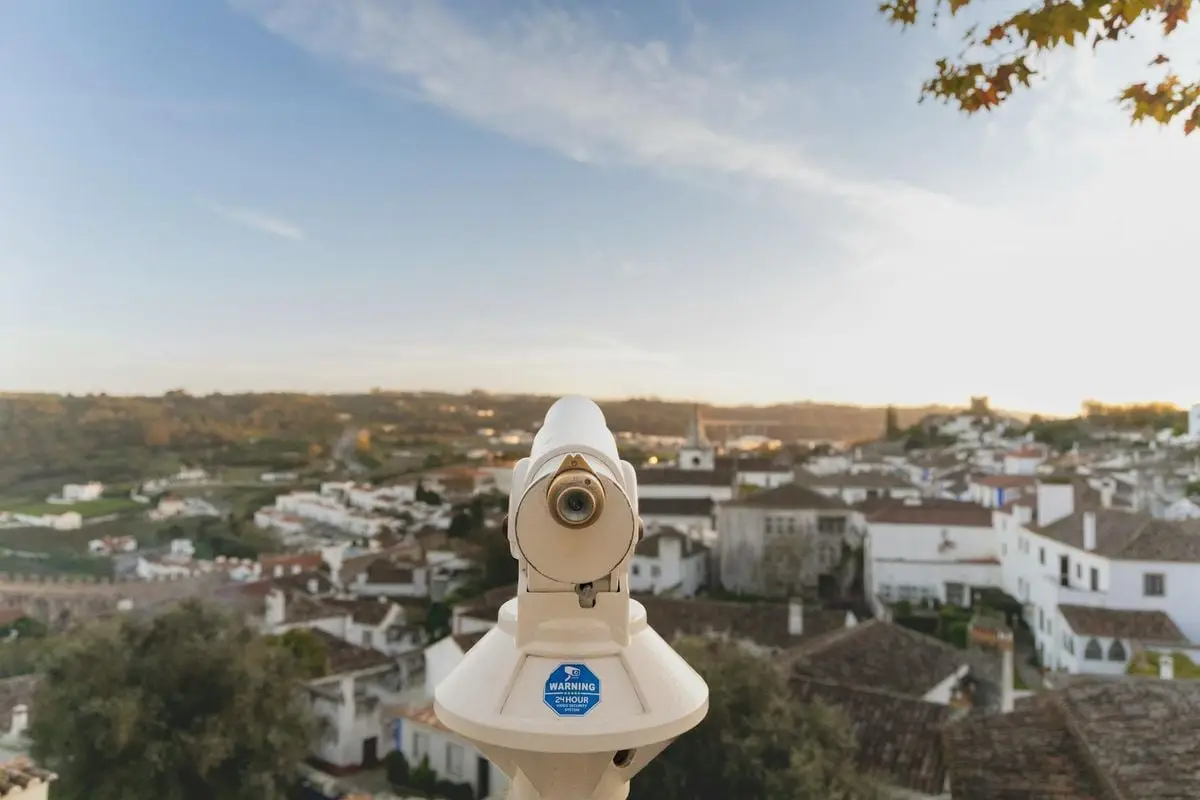 Telescope overlooking the charming rooftops and landscape of Óbidos, Portugal during daytime.