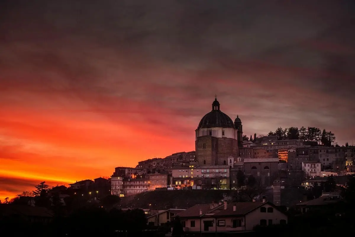Explore a serene medieval town with a stunning church against a vibrant sunset sky.