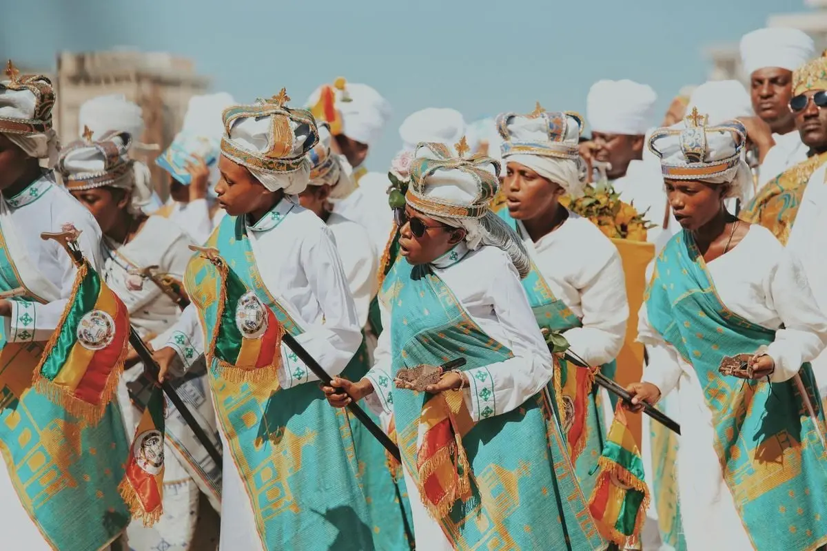 Men in vibrant traditional costumes parade during a cultural festival outdoors.