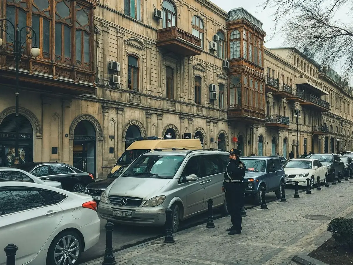 Police officer amidst traffic near historic buildings in Baku, Azerbaijan.