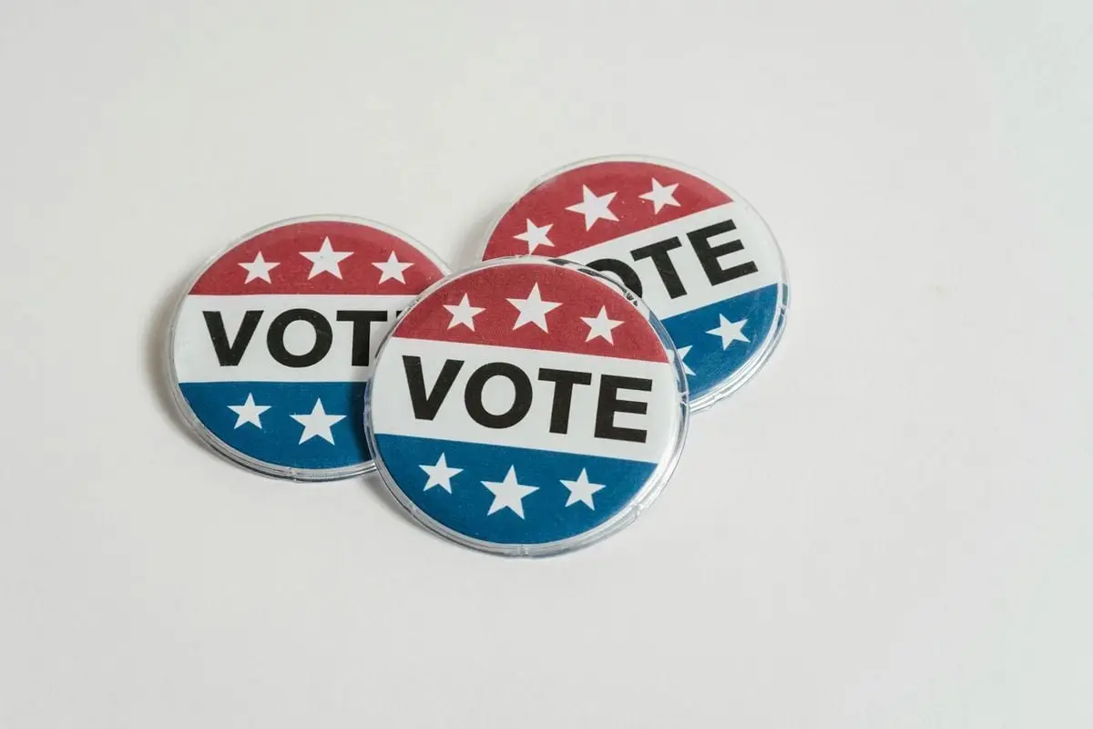 Red, white, and blue voting badges promoting elections on a clean white background.