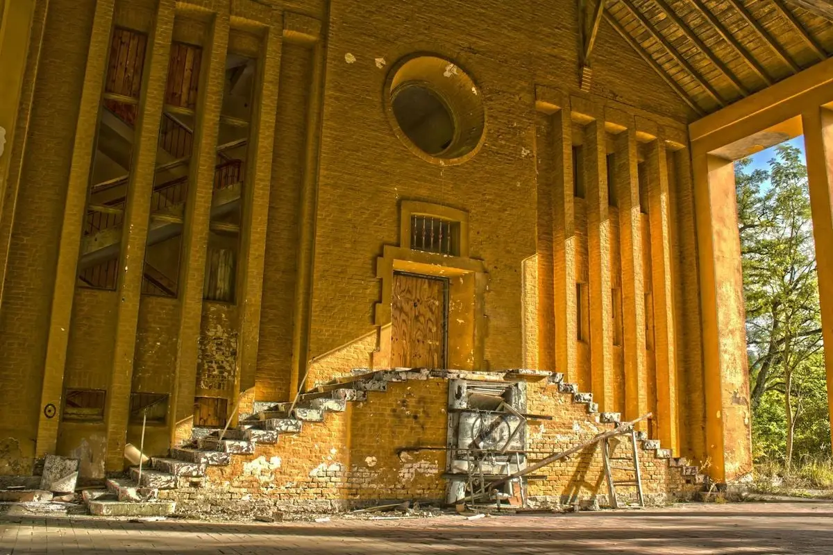 Sunlit view of an abandoned Soviet structure with broken stairs and peeling paint.