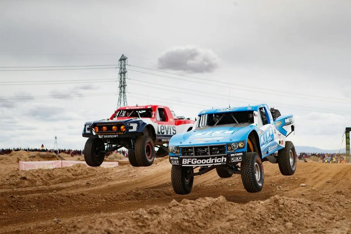 Dynamic off-road race with trucks soaring over desert terrain during a thrilling motorsport event.