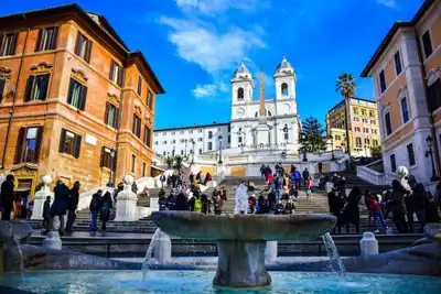 Tourists enjoying a sunny day at the iconic Spanish Steps in Rome, Italy.
