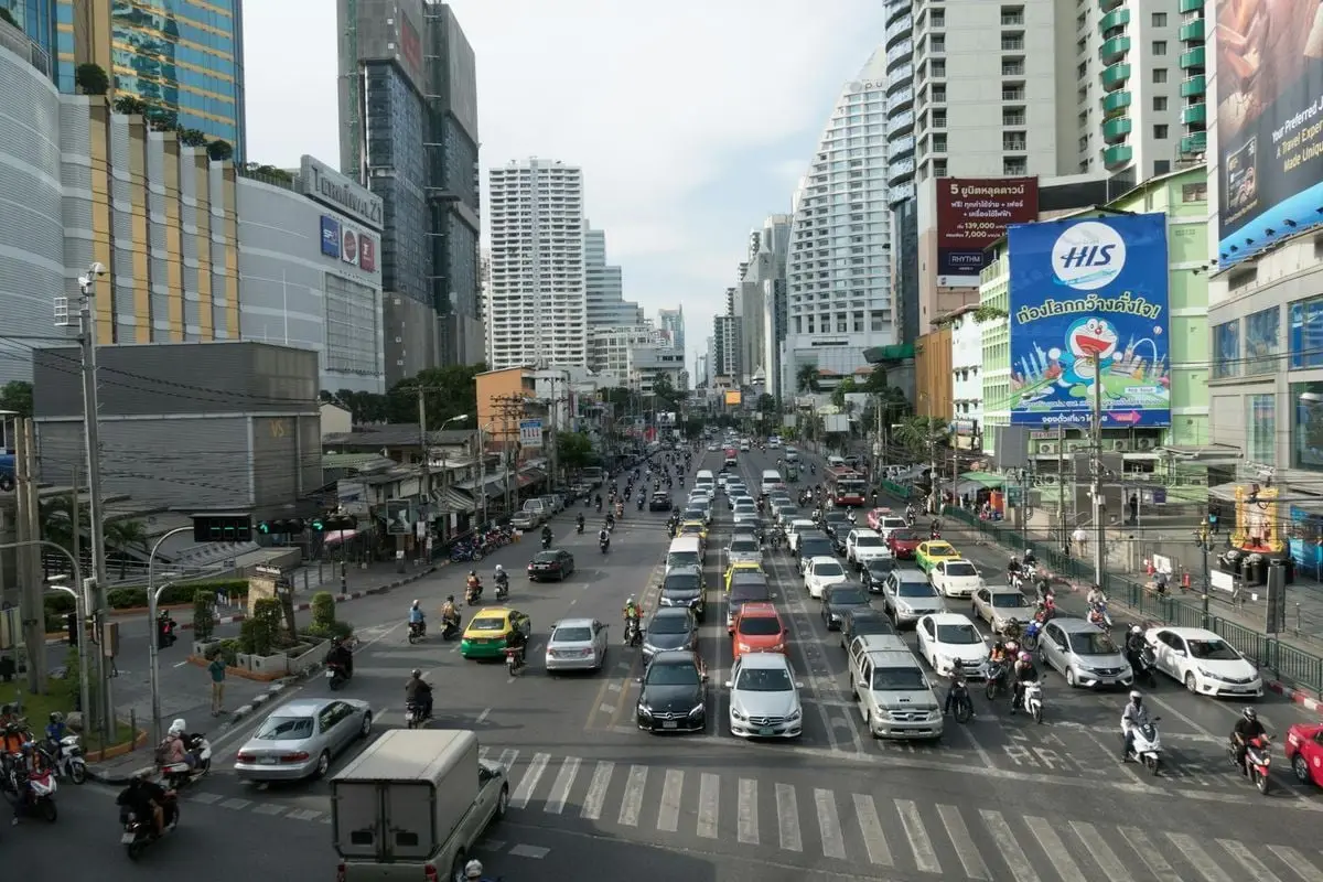 Busy street with heavy traffic and skyscrapers in downtown Bangkok during the day.