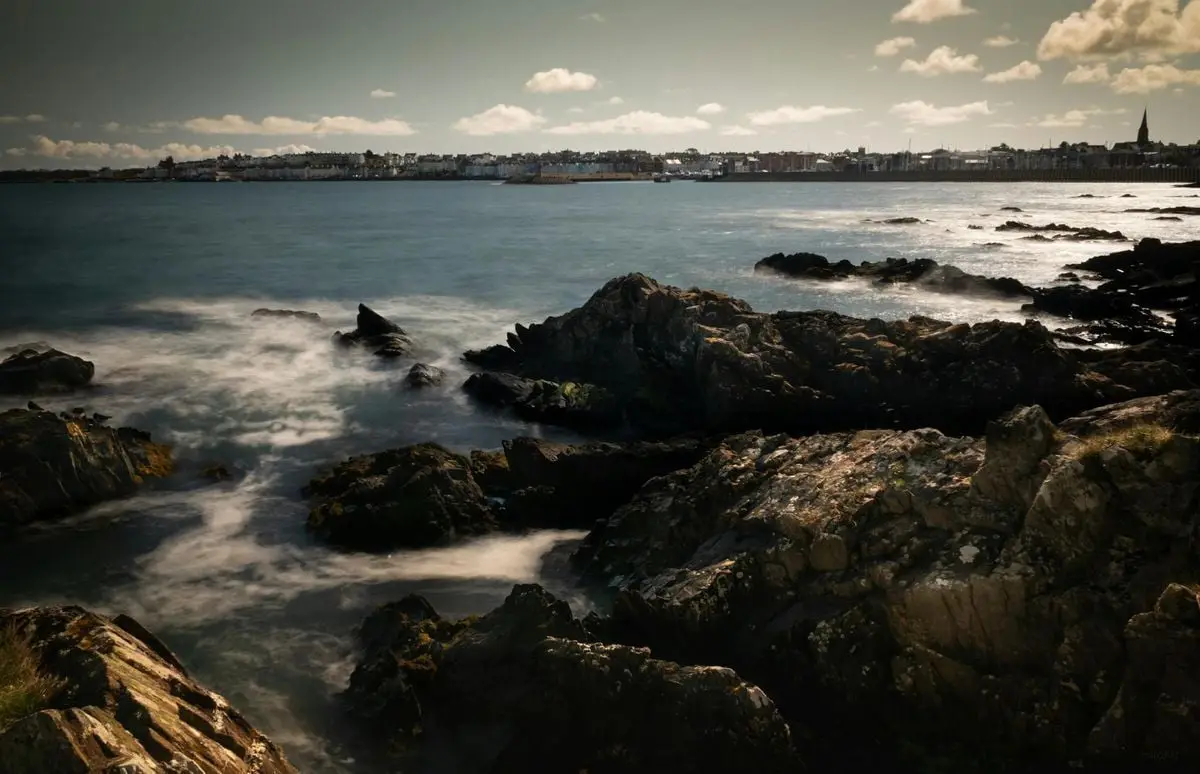 Captivating seascape of Bangor rocks and sea during daytime with a panoramic view of the town.