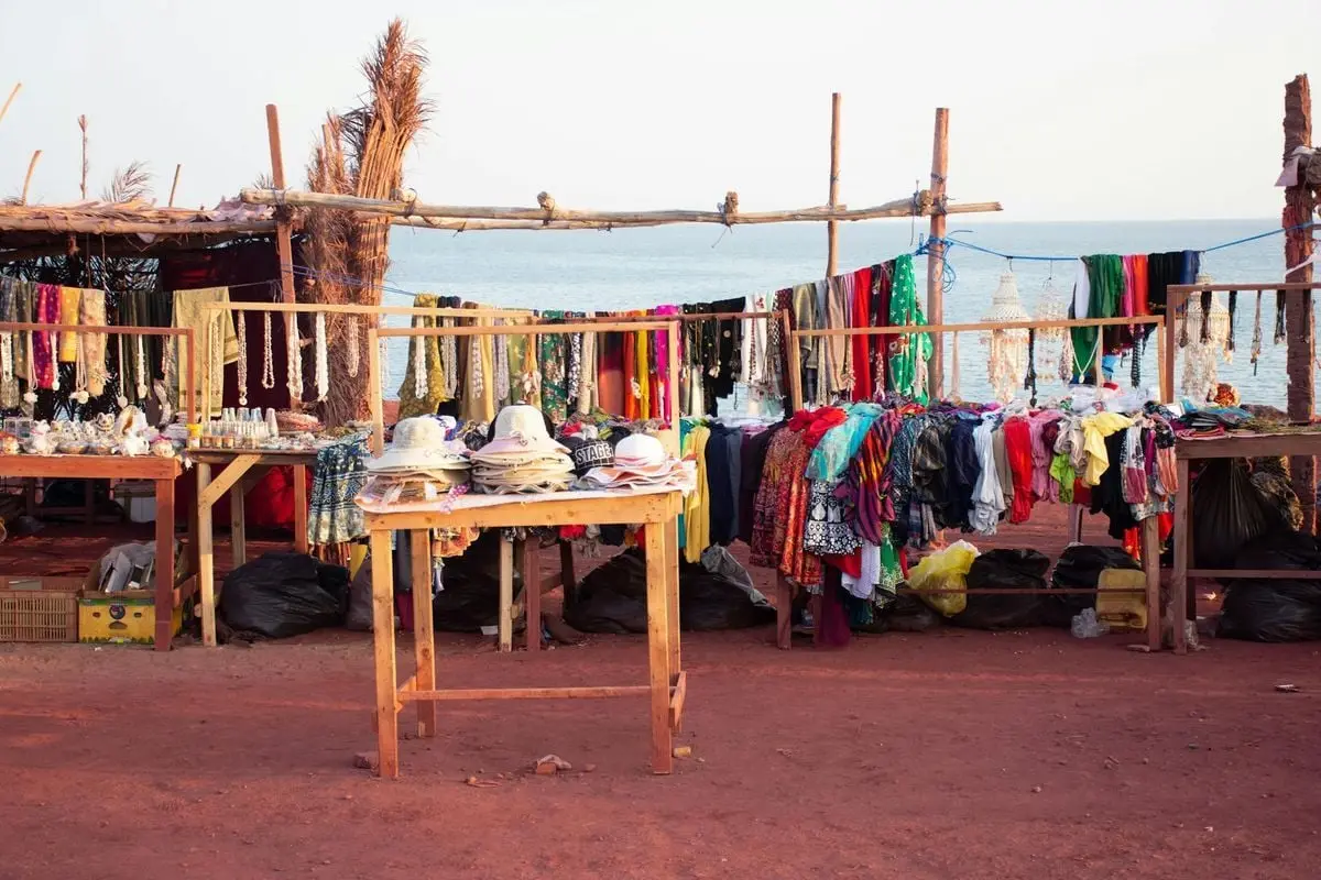 Vibrant market stalls with clothes and hats along the Hormoz beach in Iran.