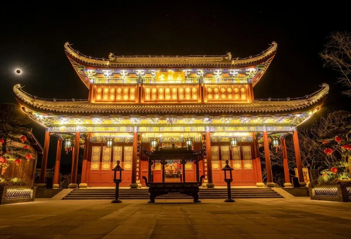 A beautifully illuminated traditional Asian temple at night, showcasing intricate architecture.