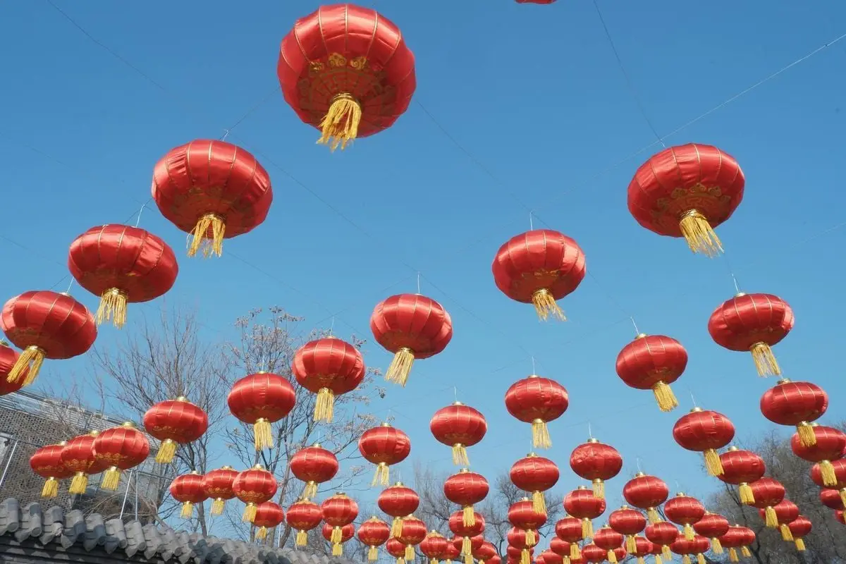 Vibrant red lanterns hanging outdoors against clear blue sky, symbolizing festive celebration.