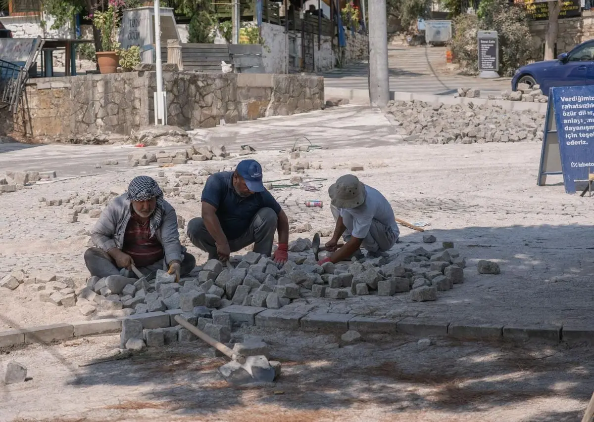 Hardworking individuals laying cobblestones on a sunny street in İzmir, Türkiye