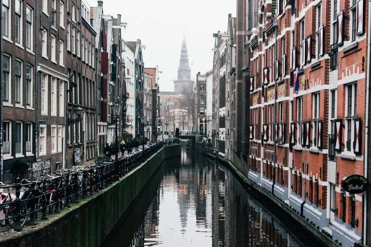 Misty view of a canal with bicycles and historic buildings in Amsterdam.