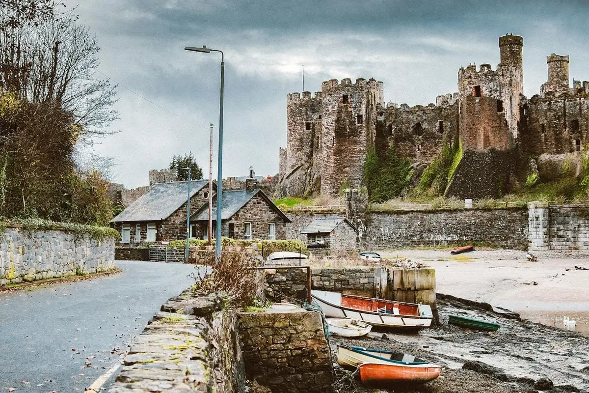 Scenic view of a historic medieval castle by the water with boats and stone buildings.