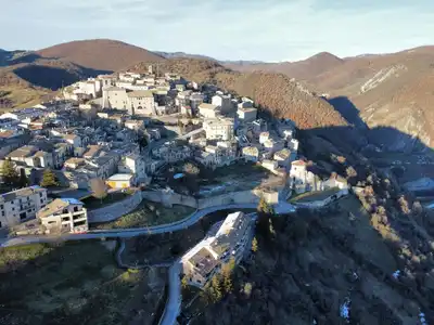 Aerial view of a charming Italian village nestled in rolling hills, showcasing traditional architecture.