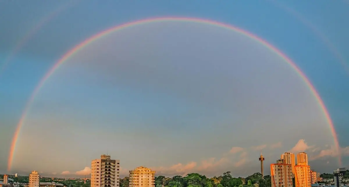 A beautiful double rainbow arcs over the cityscape of Belém, Brazil, during the day.