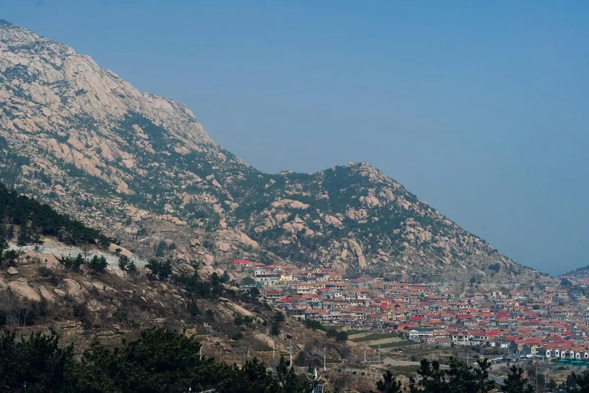 Aerial view of a town nestled in the mountains near Qingdao, showcasing natural beauty and urban harmony.