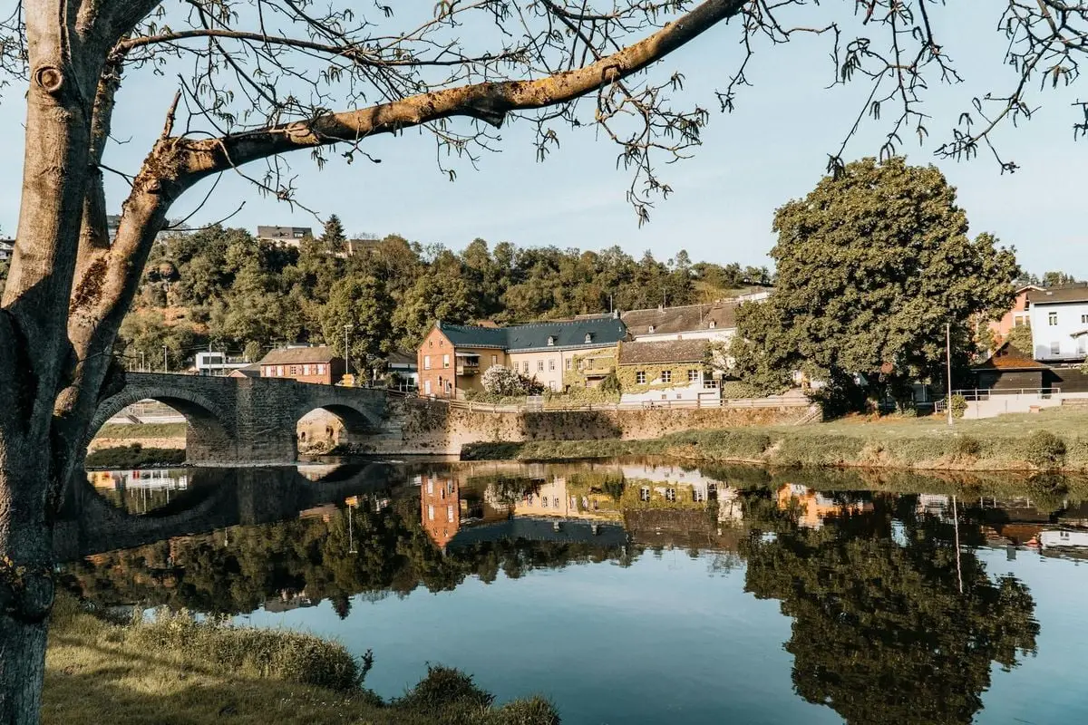 Charming Runkel town with a historic bridge reflecting in the calm river under a clear sky.