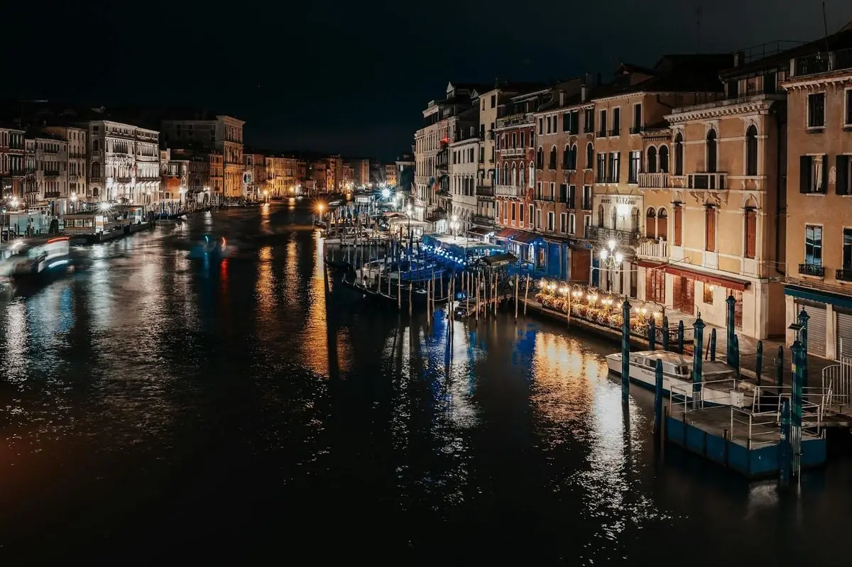 Beautiful nighttime view of the Grand Canal with historic Venetian buildings and gondolas in Venice, Italy.