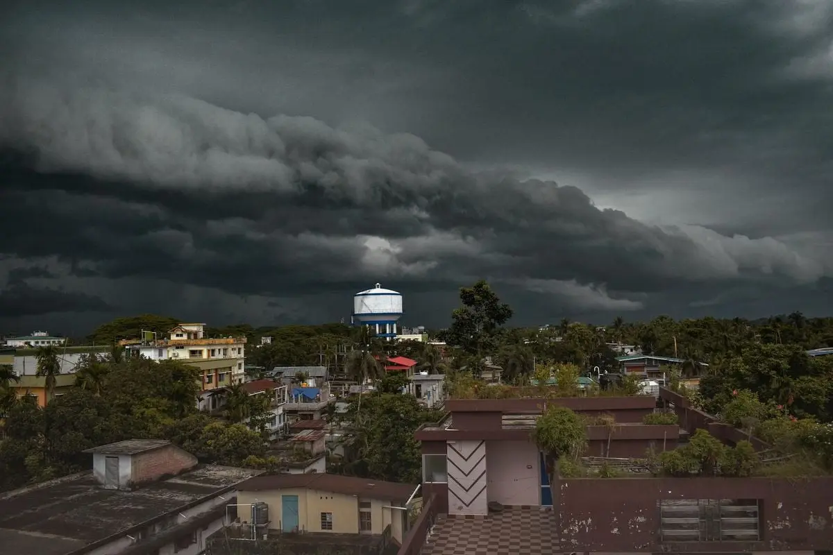 Aerial view of a small town with a water tower under dramatic storm clouds.