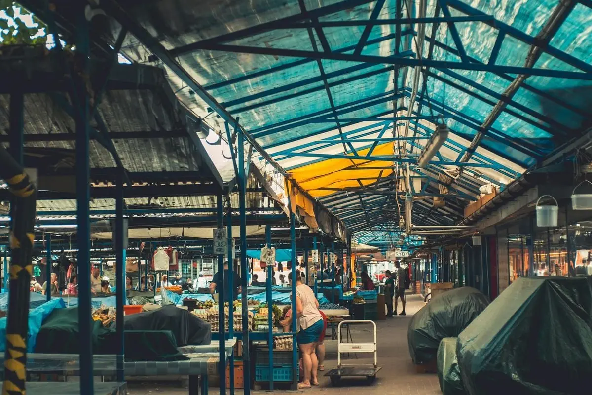 Explore the vibrant local market in Krakow, Poland, under colorful canopies.
