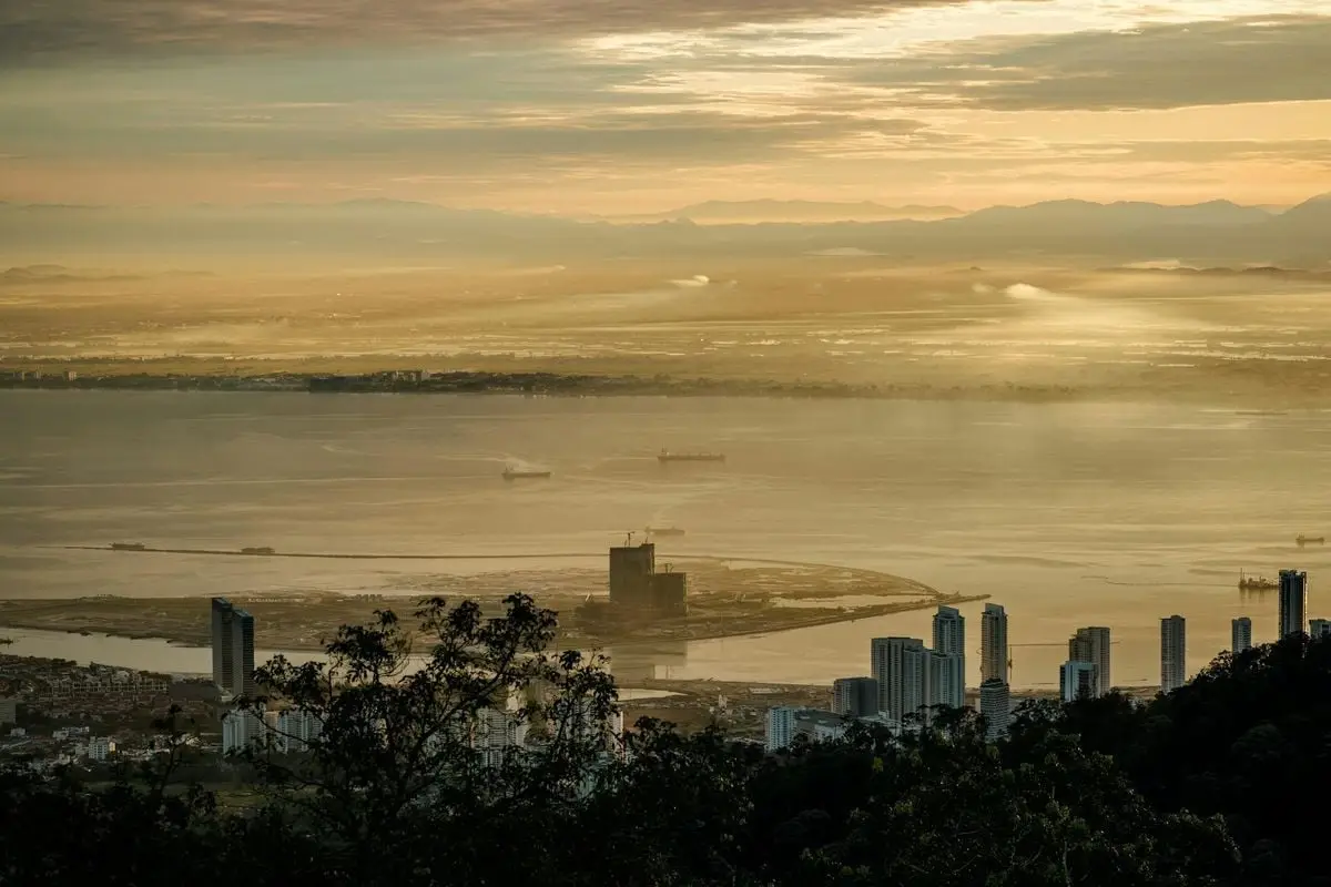 Stunning sunrise view over Penang from Bukit Bendera, Malaysia featuring skyscrapers and the coastline.