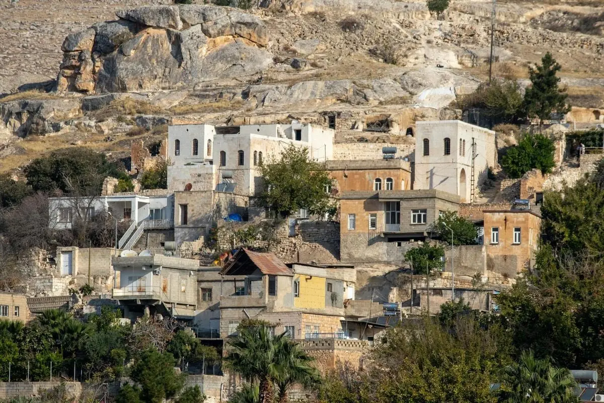 View of charming stone houses in the historic town of Halfeti, Türkiye surrounded by rocky terrain.