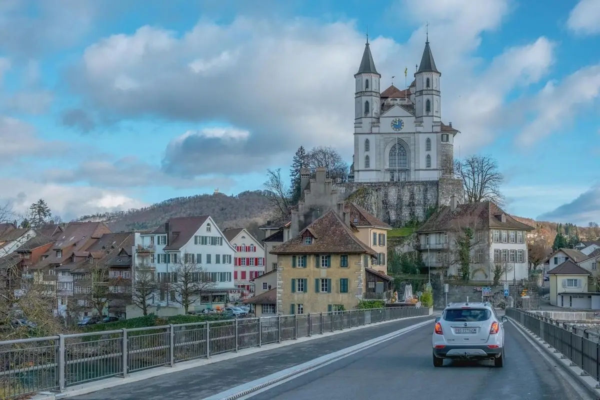 Picturesque view of Aarau, Switzerland showcasing St. Ursus Cathedral with a car crossing the bridge.