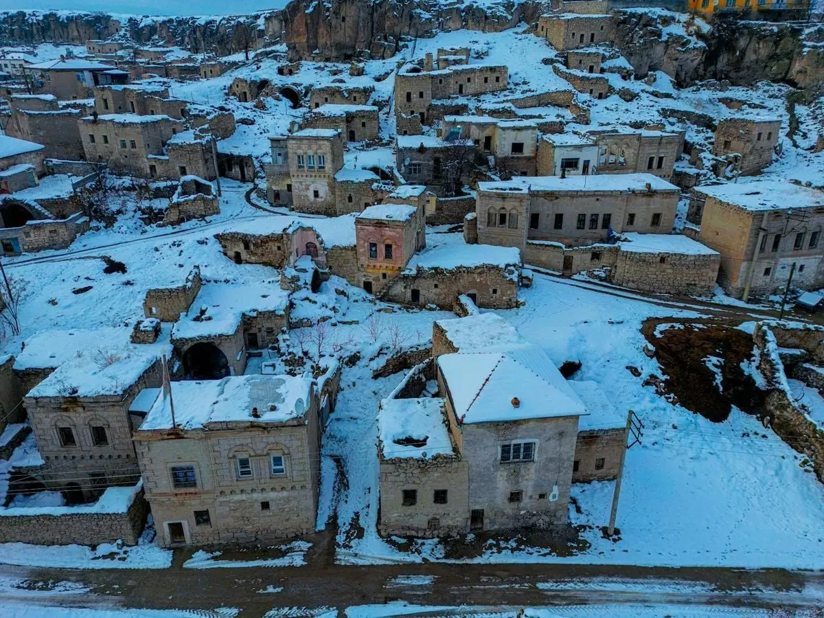 Aerial shot of a historic stone village covered in snow during winter.