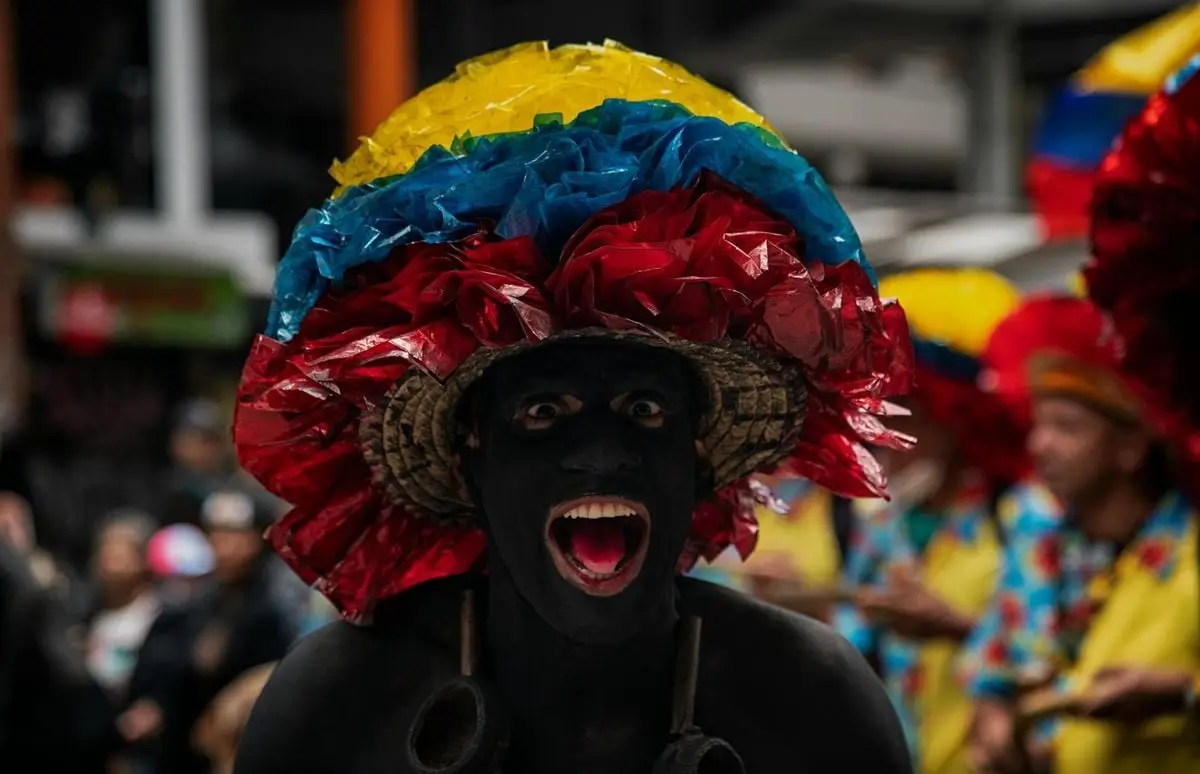A colorful carnival participant in vibrant attire and body paint in Bogotá, Colombia.