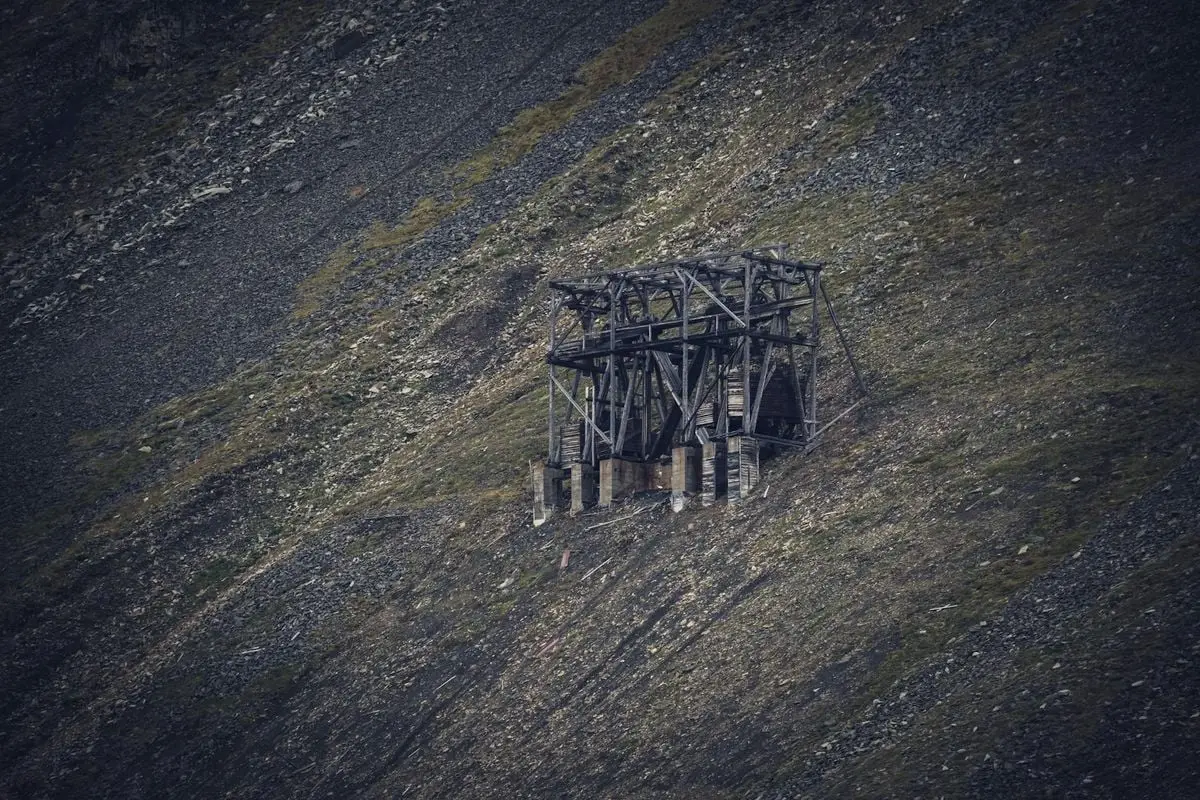 A vintage wooden mine structure on a barren rocky hill, showcasing a deserted rural landscape.