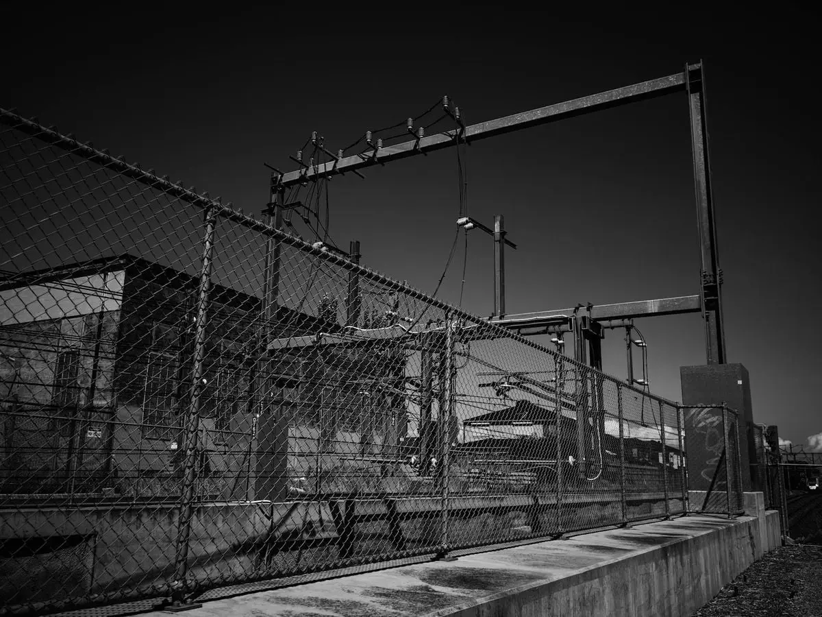 Black and white photo of an industrial power station behind a metal fence.