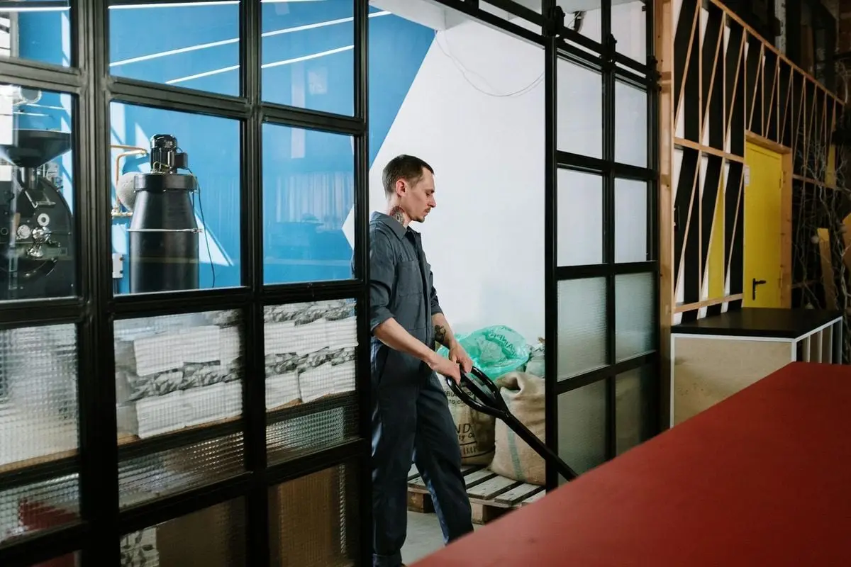 A man in uniform operates machinery in a coffee roastery, highlighting industrial work.