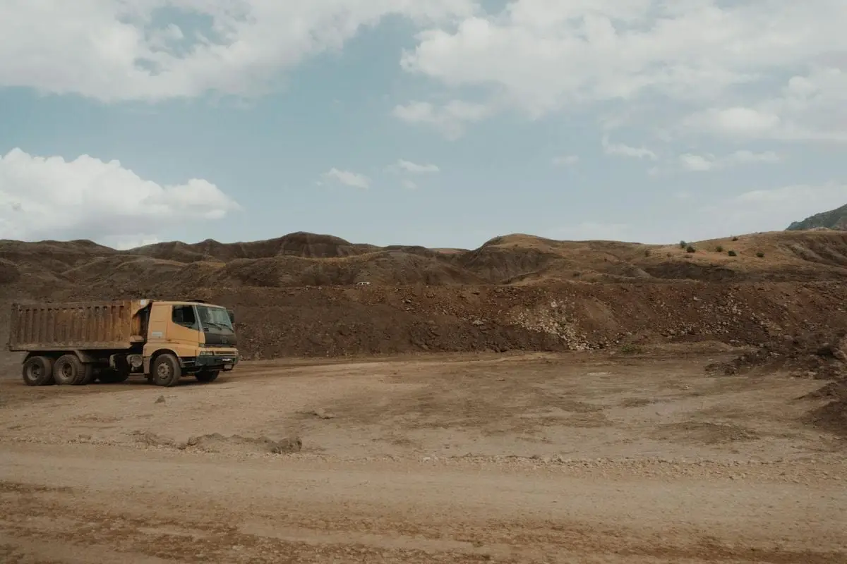 A solitary dump truck at a quarry site under a cloudy sky.