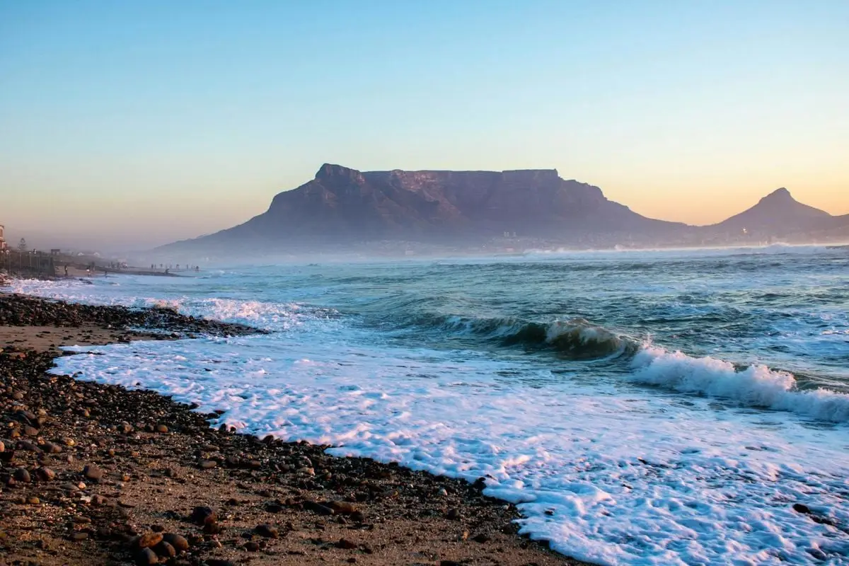 Stunning sunset view of Table Mountain and sea waves from Blouberg Beach.