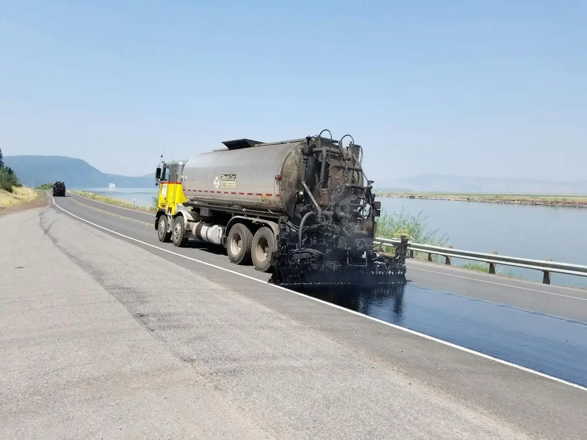Paving truck applying asphalt on a highway near a lake in Klamath Falls, Oregon.