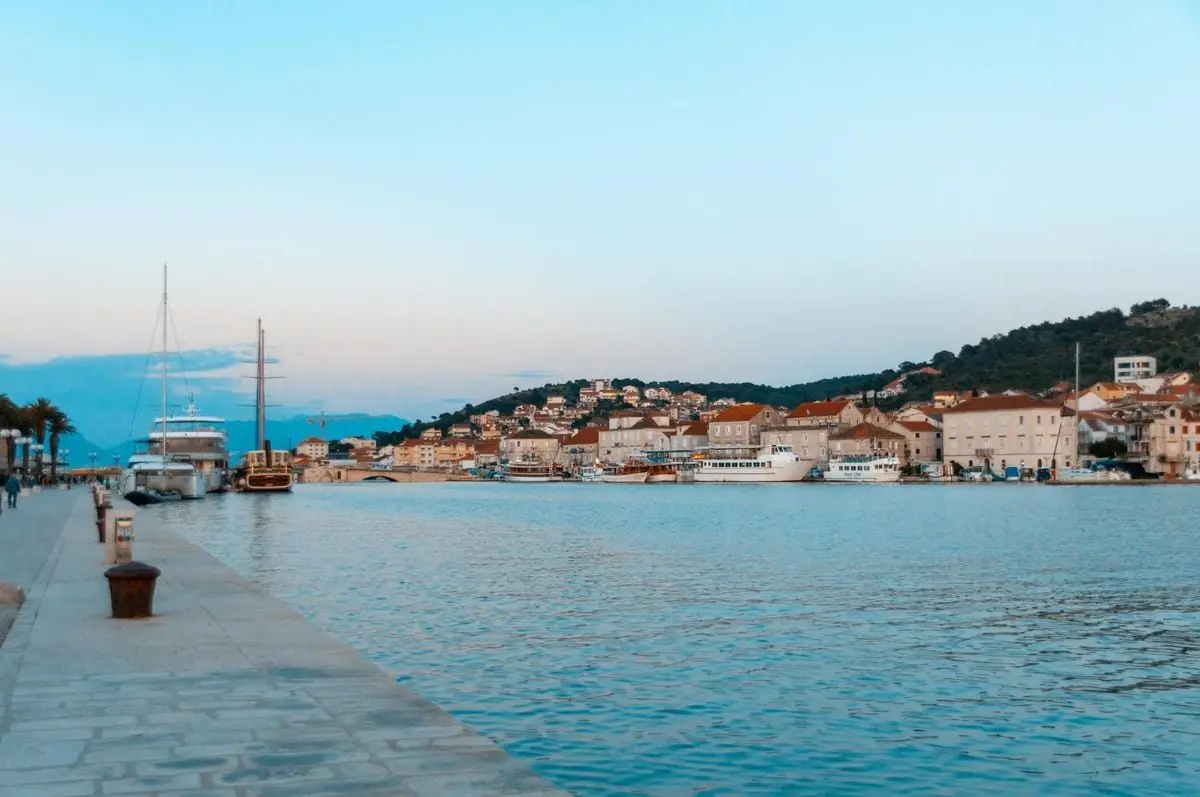 Picturesque harbor in Trogir, Croatia with boats and historic buildings at sunset.