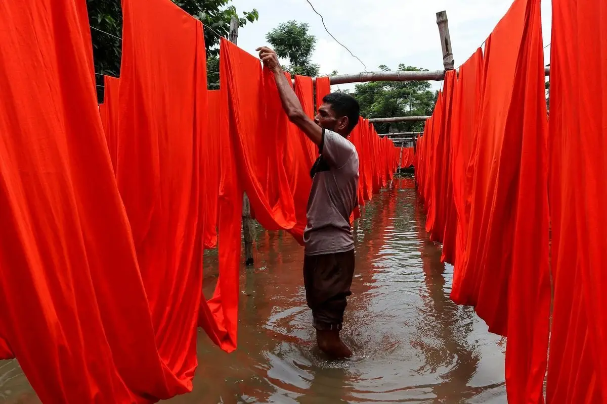 Man drying red fabric outdoors in Narayanganj, Bangladesh.