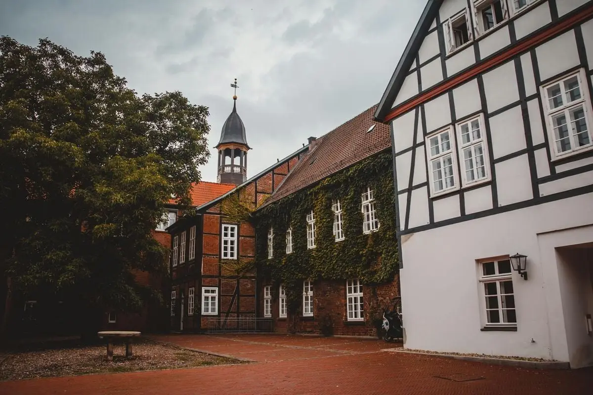 Picturesque European courtyard featuring traditional half-timbered buildings and lush greenery.