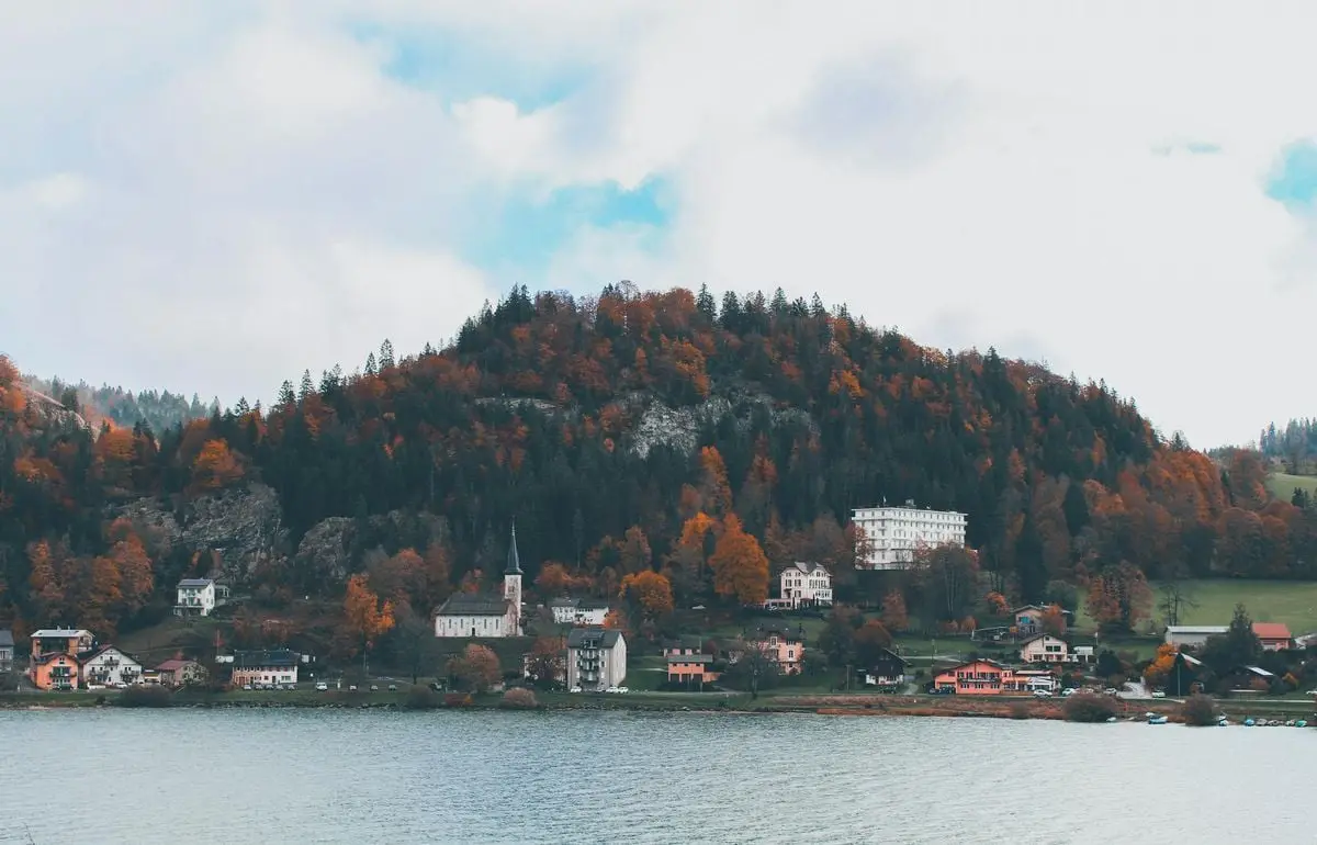 Charming European village nestled by a lake with vibrant autumn foliage and tranquil surroundings.