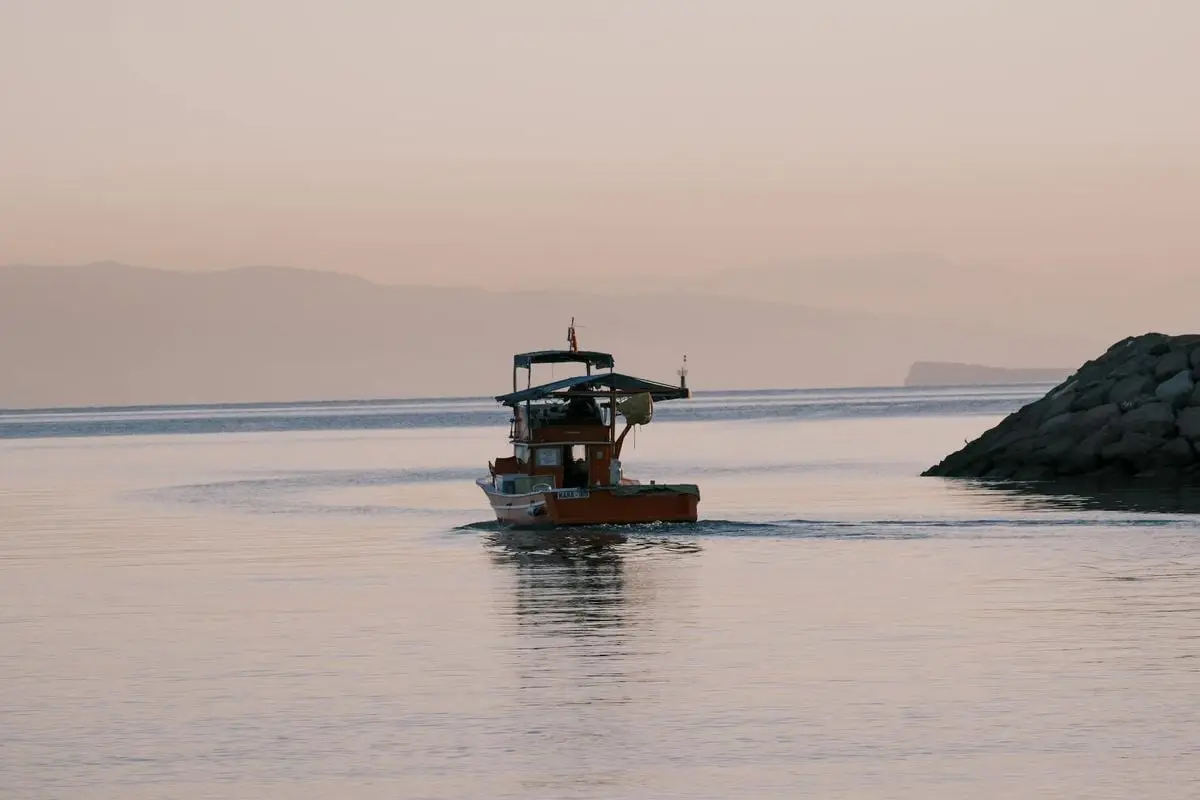 Motorboat navigating calm waters near the shore at dusk in Foça, İzmir, Türkiye.