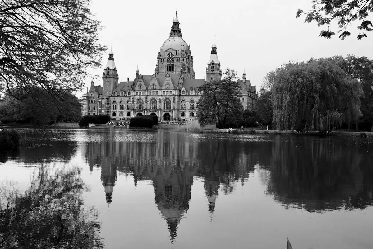 Black and white photo of New Town Hall in Hannover, reflected in the pond.