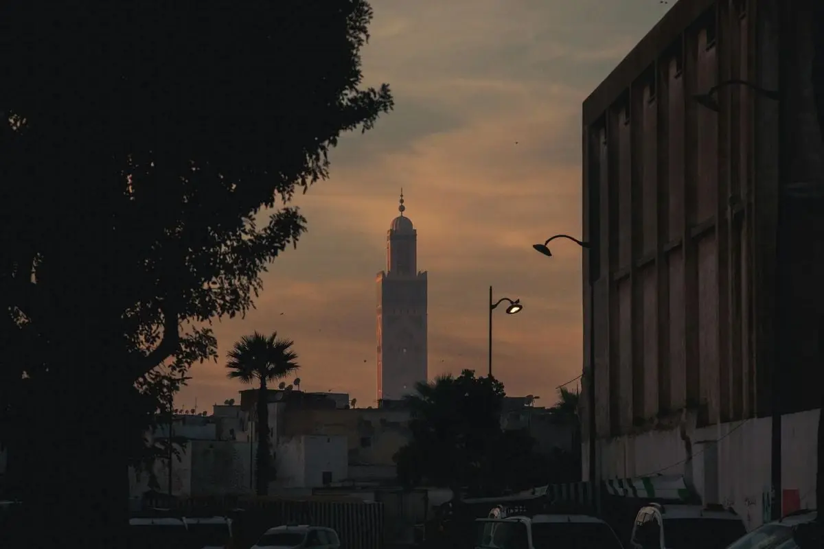 Hassan II Mosque silhouetted against a vibrant sunset in Casablanca, showcasing Moroccan architecture.