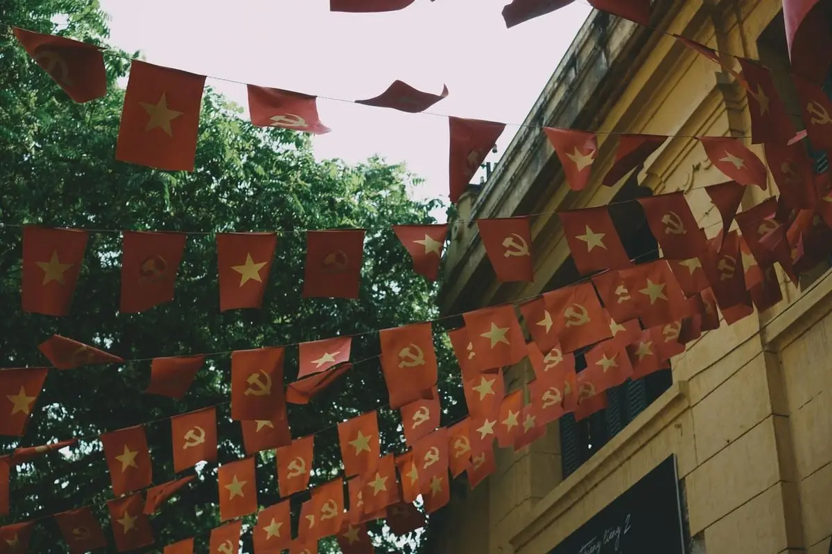 Rows of Vietnamese flags with stars and hammers against urban architecture in Hanoi.